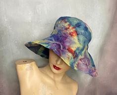 "A big floppy beach hat hand ice tie dyed in blue, green, yellow and red.  It has a drawstring around the inside band to secure fit from the wind.  The hat is by Scala.  The brim is 5\", the crown is 3\", the top diameter is 5 1/2\" and the the inside band is up to 23\" around. Hand or gentle machine wash separately. Excellent condition. Catalog # 8562" Blue Summer Hat One Size, Adjustable Multicolor Sun Hat, Adjustable Pre-washed Bucket Hat, Adjustable Tie Dye Hats For Summer, Adjustable Tie Dye Summer Hat, Summer Tie-dye Adjustable Hat, Blue Bucket Hat For Beach, One Size Fits Most, Colorful Brimmed Sun Hat For Summer, Fun Wide Brim Sun Hat For Festivals