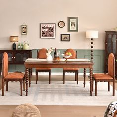 a dining room table with four chairs and a rug on the floor in front of it