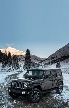 a black jeep parked on the side of a snow covered road in front of mountains