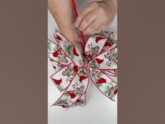 a person tying a bow on top of a white table with red and green decorations