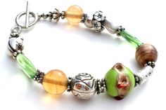 Fashion Jewellery - This is a bracelet with a green wedding cake bead, green and amber glass beads, and silver flowers, frog and spacers. It is 8" long, beads vary from 4mm to 17mm in width. Green Wedding Cake, Silver Bead Bracelet, Bead Bracelets, Silver Bead, Green Wedding, Silver Flowers, Amber Glass, Silver Beads, Pandora Charm Bracelet