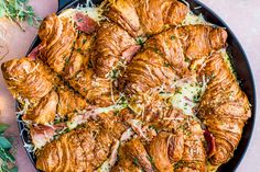 a pan filled with croissants and cheese on top of a pink table