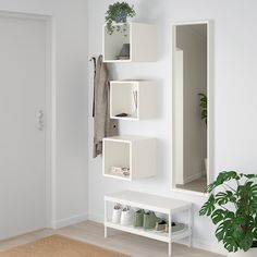 a white shelf with shoes and plants on it next to a planter in the corner