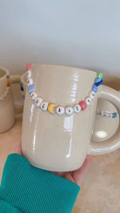 a hand holding a coffee mug with beads on it