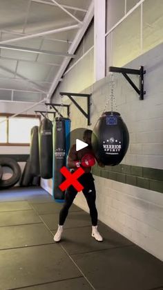 a woman in black and red boxing gear is holding a punching bag with one hand