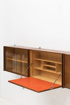 a wooden cabinet with shelves and an orange mat