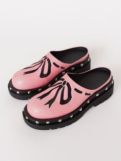 Plumbers are big fans of clogs, wonder why…Your new summer shoe has finally arrived! In pink, these slip-on clog shoes are made from 100% vegan leather with a contrasting cleated rubber sole that has a slight heel, and stud detailing all the way around. They have a side gusset which helps give ease and comfortability to the wear of the shoe. Across the body of the shoe is an embroidered bow detailing in a contrasting black. Pink Rubber Sole Slip-ons For Spring, Spring Flat Clogs With Rubber Sole, Trendy Slip-on Clogs With Lug Sole, Trendy Clogs With Lug Sole And Round Toe, Spring Leather Clogs With Lug Sole, Spring Slip-on Clogs With Rubber Sole, Pink Slip-ons With Rubber Sole, Pink Spring Mules With Rubber Sole, Spring Pink Mules With Rubber Sole