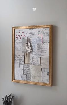 a wooden frame with many pieces of paper attached to it, hanging on the wall