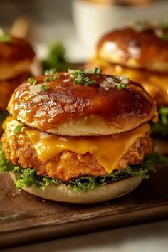 two chicken burgers with cheese and lettuce on a wooden tray next to other food items