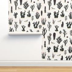 a white wall with black and white cacti on it next to a wooden floor