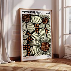 a poster with flowers on it sitting in front of a white wall next to a window