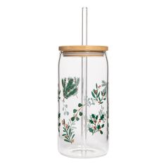 a glass jar with a wooden lid filled with berries and leaves on the inside is holding a straw