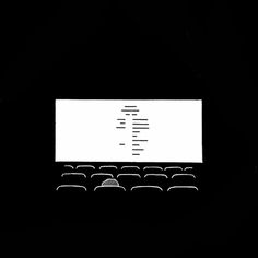 a black and white photo of an old typewriter with the screen turned on, in front of rows of chairs