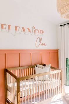 a baby's room with pink and white walls, a crib and cactus plant on the wall