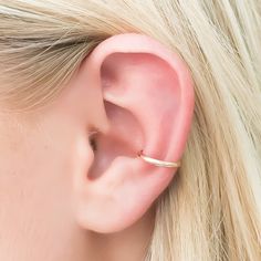 a woman with blonde hair wearing a gold ear cuff