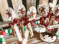 hand holding spoons with cookies and marshmallows in them on wooden table