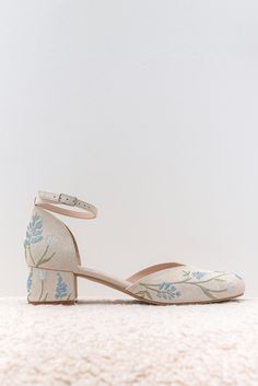 a pair of white shoes with blue flowers on them