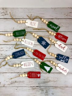 wooden name tags are hanging on a white wood planks with twine and bead