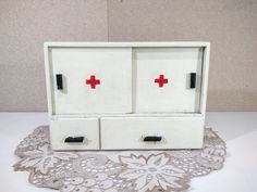 two drawers with red crosses on them are sitting on a doily covered tablecloth