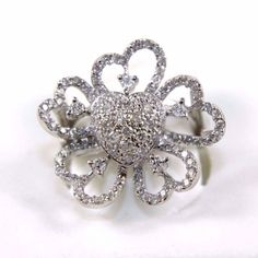 a diamond flower shaped ring on a white surface with lots of diamonds in the middle