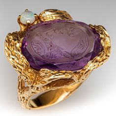 This fabulous ring features a beautifully carved amethyst intaglio set askew within a textured organic semi-bezel. The person depicted in the carving looks up towards a small prong set round opal which accents the design. The wood bark textured ring is crafted in 14k yellow gold and is currently a size 6.75. Vintage Amethyst Rings, Extravagant Dresses, Amethyst Rings, Amethyst Cocktail Ring, Amethyst Ring Vintage, Bark Texture, Wood Bark, Amethyst And Diamond Ring, Bold Rings