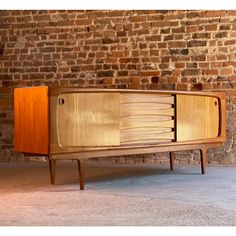 a wooden cabinet sitting in front of a brick wall