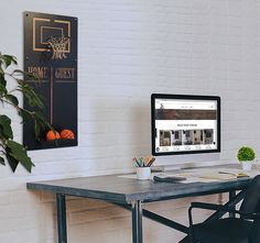 a desk with a computer on it in front of a white brick wall