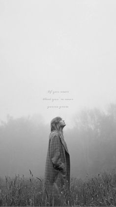 a woman standing in the middle of a field on a foggy day