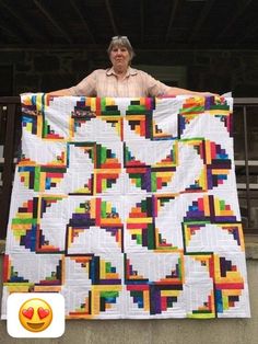 a man holding up a large colorful quilt