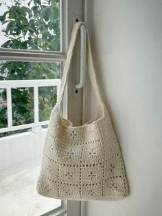 a crocheted bag hanging on the side of a window sill next to a white door