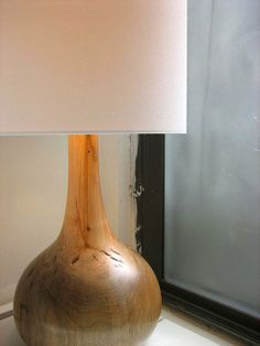 a wooden table lamp sitting on top of a window sill