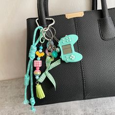 a handbag with some charms hanging from it's side and a cell phone attached to the handle