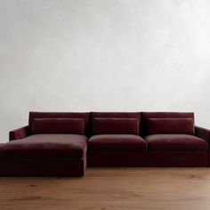 a red couch sitting on top of a hard wood floor next to a white wall