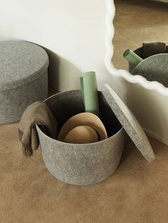 two round storage bins with hats in them on the floor next to a mirror