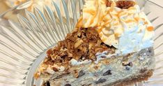 a piece of cake with nuts and whipped cream on top sits in a glass bowl