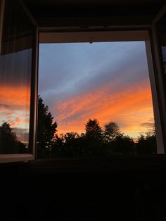 the sunset is seen through an open window with trees in the foreground and clouds in the background