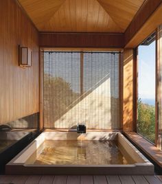 an indoor jacuzzi tub in the middle of a wood floored room with large windows