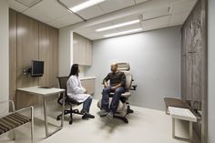 an office with a chair, desk and television on the wall in front of it