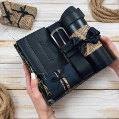 a person is holding a black book with a bow on it and wrapped in twine