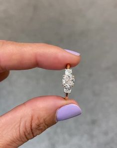 a woman's hand holding an engagement ring with a diamond on the middle finger