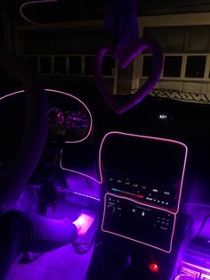 the interior of a car with purple lights on it and a heart hanging from the ceiling