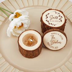 three pieces of wood with wedding rings in them on a plate next to a flower