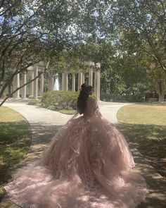 a woman in a pink dress is sitting on the ground near some trees and grass