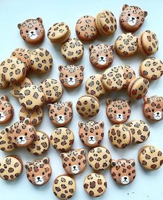 leopard print wooden buttons on a white surface with other wood buttons in the shape of cheetah's heads