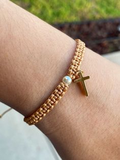 a close up of a person wearing a bracelet with a cross and pearls on it