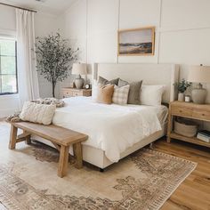 a bedroom with white walls and wood floors has a large rug on the floor next to the bed