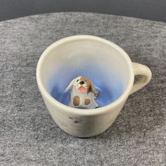 a small ceramic dog in a cup on a table