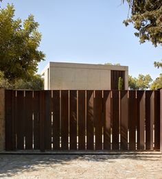 a wooden fence is in front of a concrete building and trees on the other side