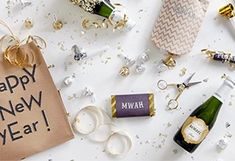 a new year's eve gift bag surrounded by champagne bottles and confetti