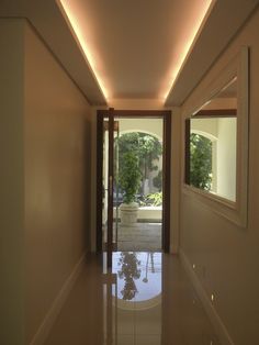 an empty hallway with mirrors and lights on the walls, leading to a patio area